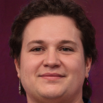 Smiling person with short hair against a purple backdrop